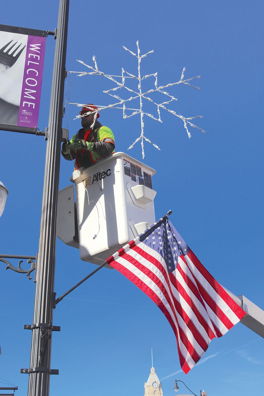 A Main Street light pole is adorned with a snowflake Tuesday morning by Street Department employee Tom Edwards.